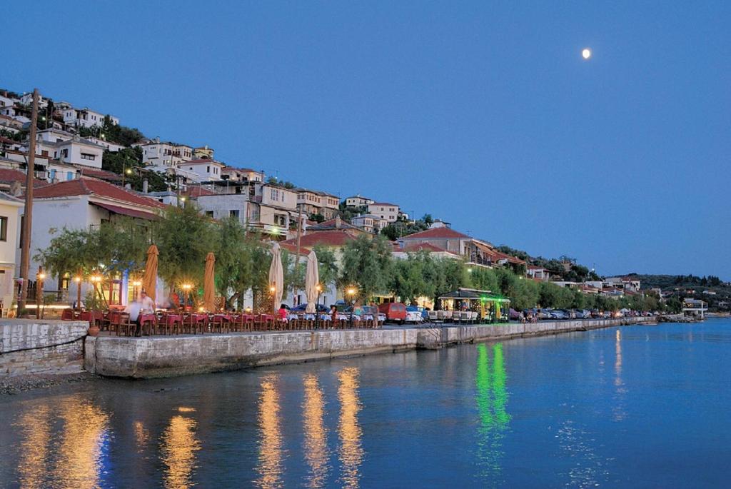 a river with tables and chairs next to a town at Katia Hotel in Afissos