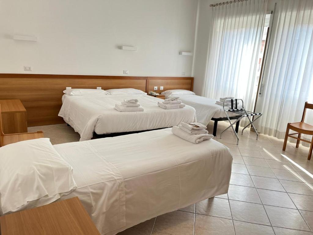 een hotelkamer met 3 bedden met witte lakens bij La Casa di Nazareth in Rome