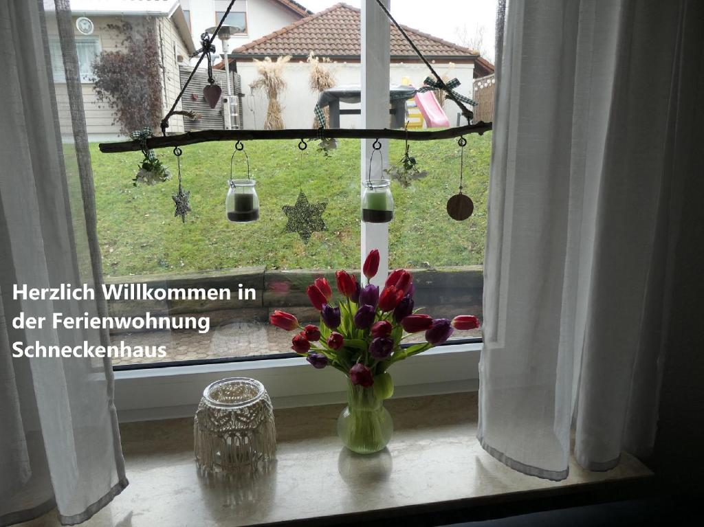 un jarrón de flores sentado en un alféizar de la ventana en Ferienwohnung Schneckenhaus, en Ofterdingen