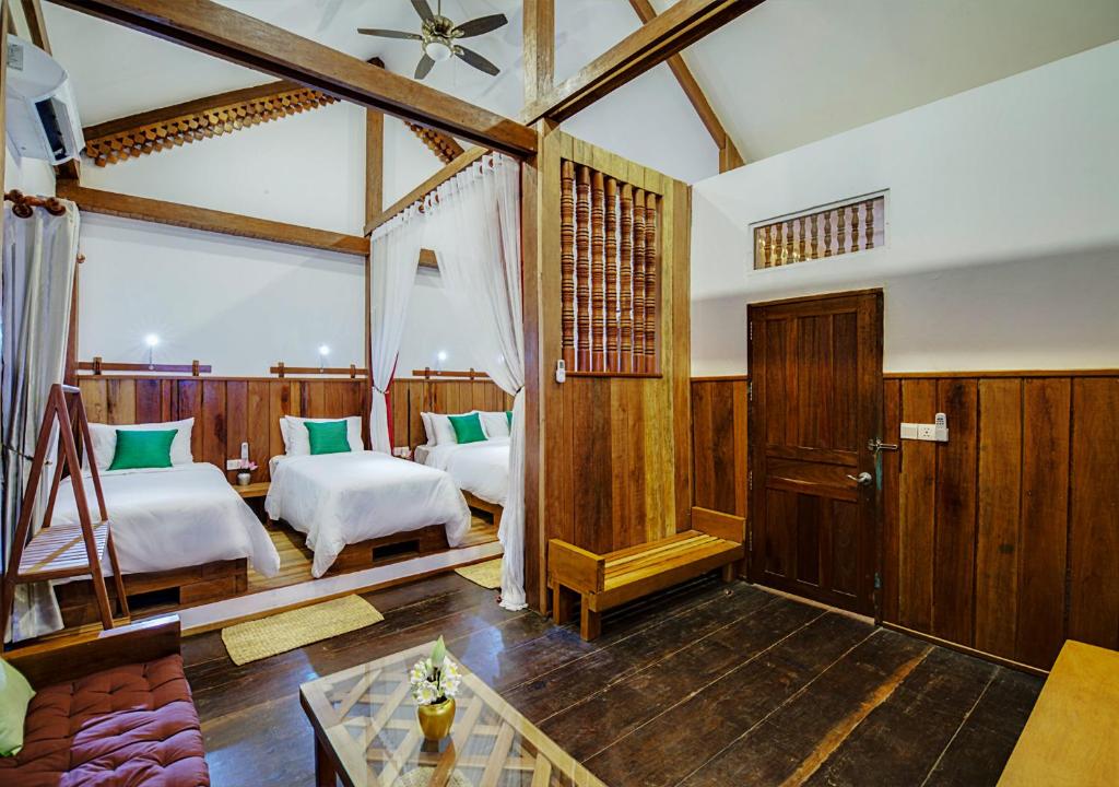 a bedroom with two beds and a table at Maison Model d'Angkor in Siem Reap