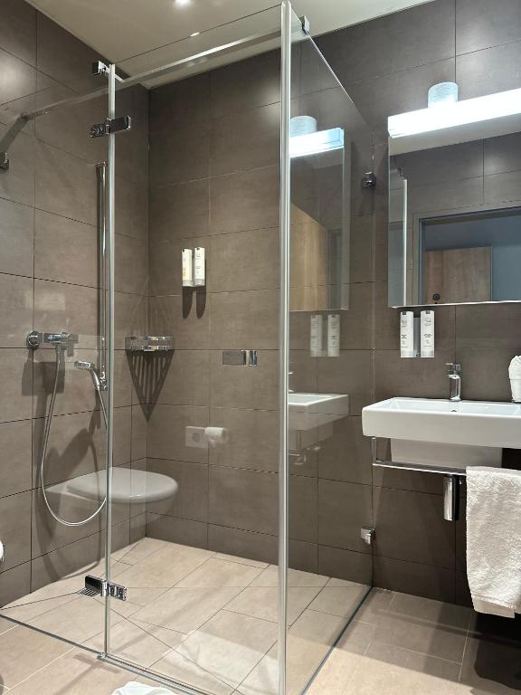 a bathroom with a shower and a sink at Plaza Hotel Winterthur in Winterthur