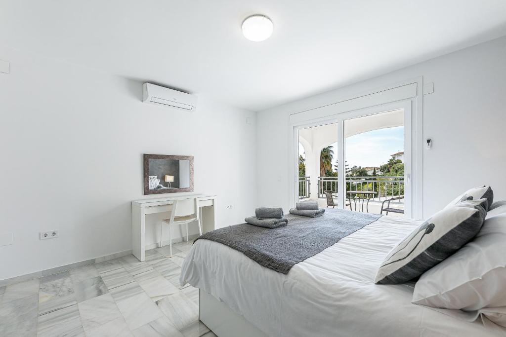 Biała sypialnia z dużym łóżkiem i balkonem w obiekcie Luxury villa with Private Pool Benalmadena w mieście Benalmádena