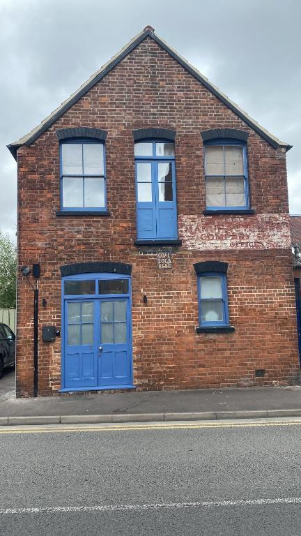 a brick building with blue doors on a street at Upstairs river apartment in Gloucester