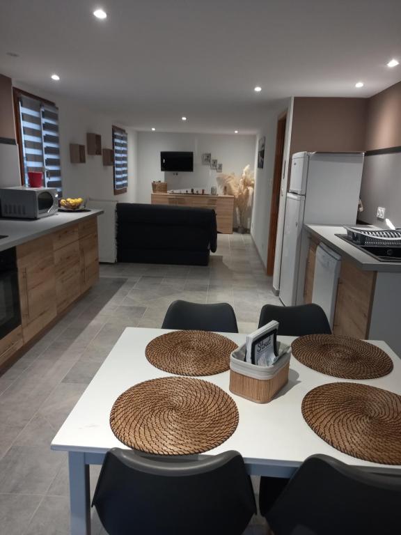 cocina y sala de estar con mesa y sillas en Gîte LA FONTAINE DU MARAIS en Pendé