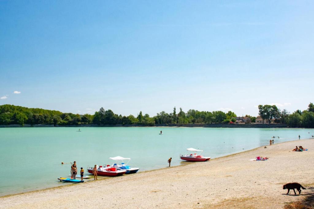 people on a beach with boats in the water at Camping Etang de la Bonde in Sannes