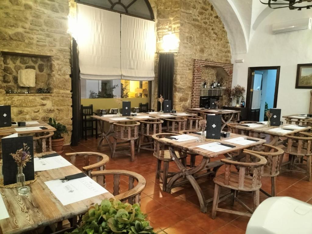 a restaurant with wooden tables and chairs in a room at Hotel Tugasa Convento San Francisco in Vejer de la Frontera