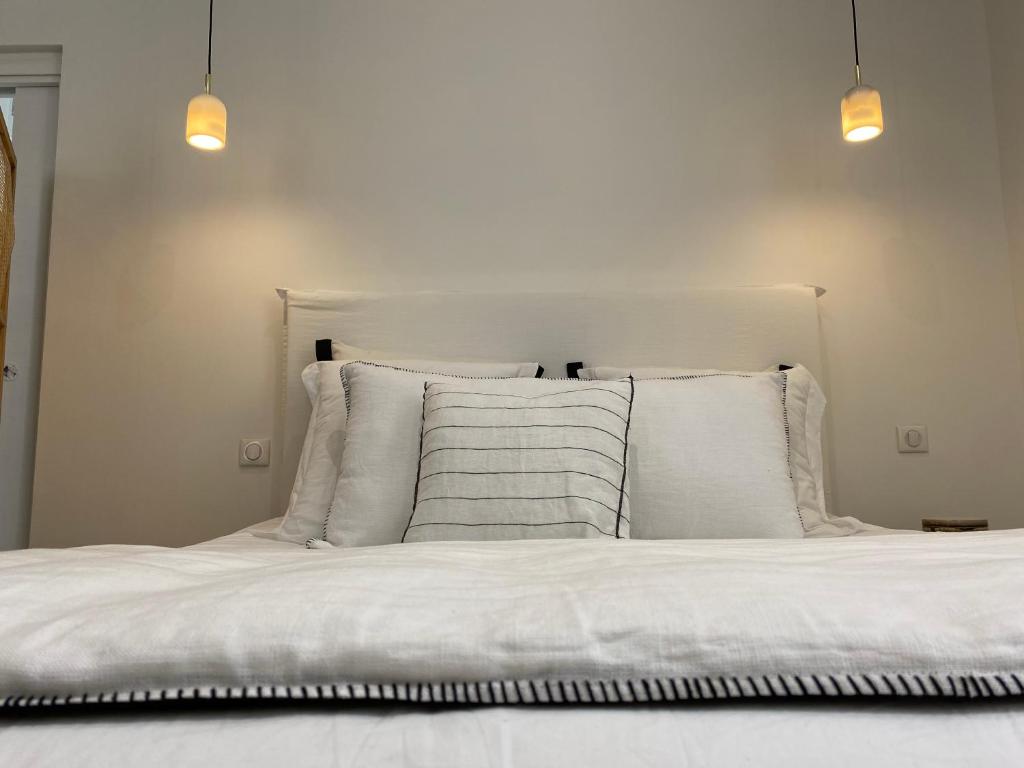 a white bed with white pillows and two lights at Belle vue sur mer, très près du port de Sanary in Sanary-sur-Mer