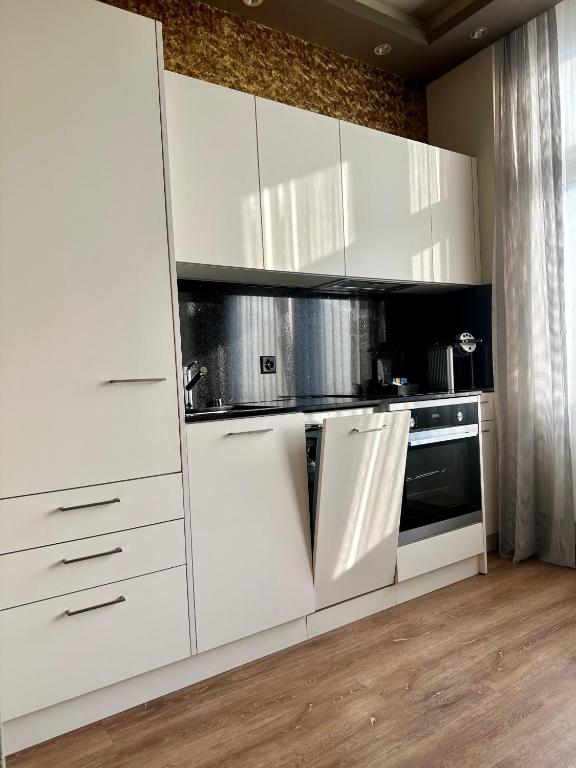 a white kitchen with white cabinets and a microwave at Plaza Hotel Winterthur in Winterthur