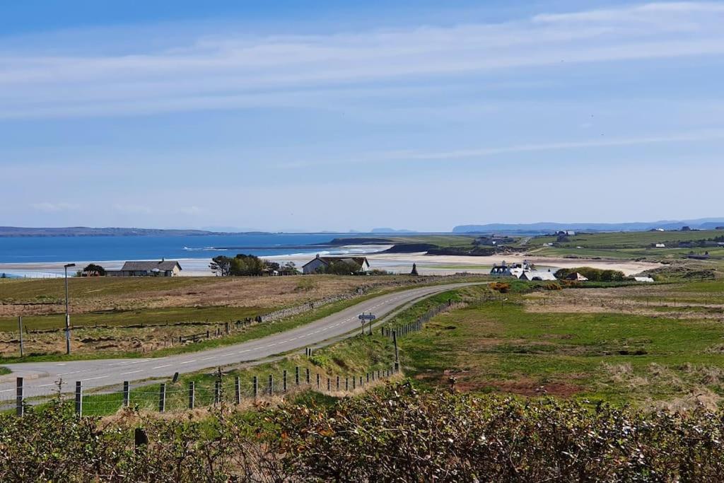 a road leading down to a beach and the ocean at Mackenzie 25 in Stornoway