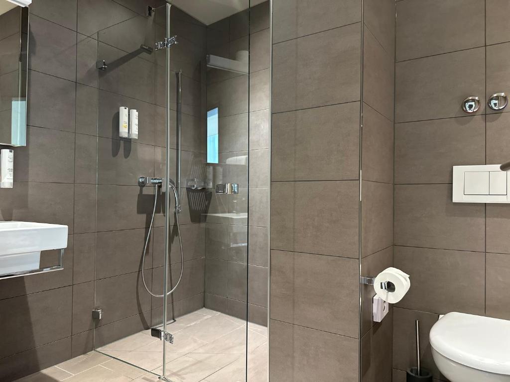 a bathroom with a shower with a toilet and a sink at Plaza Hotel Winterthur in Winterthur