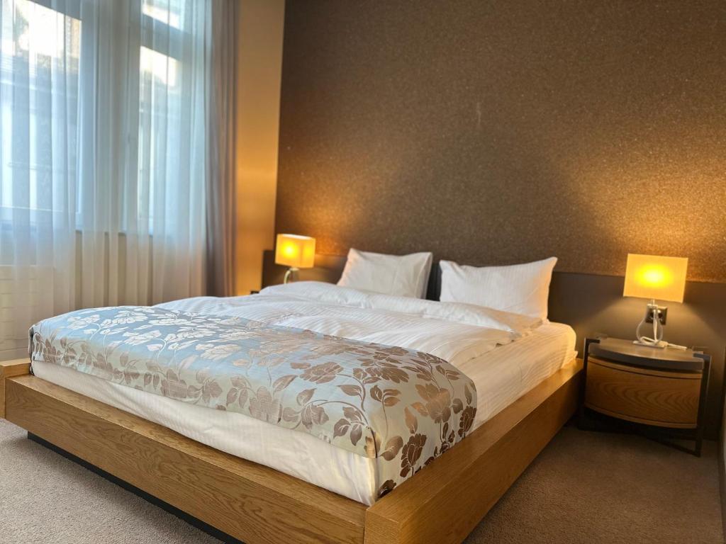 a bedroom with a large bed with two lamps at Plaza Hotel Winterthur in Winterthur