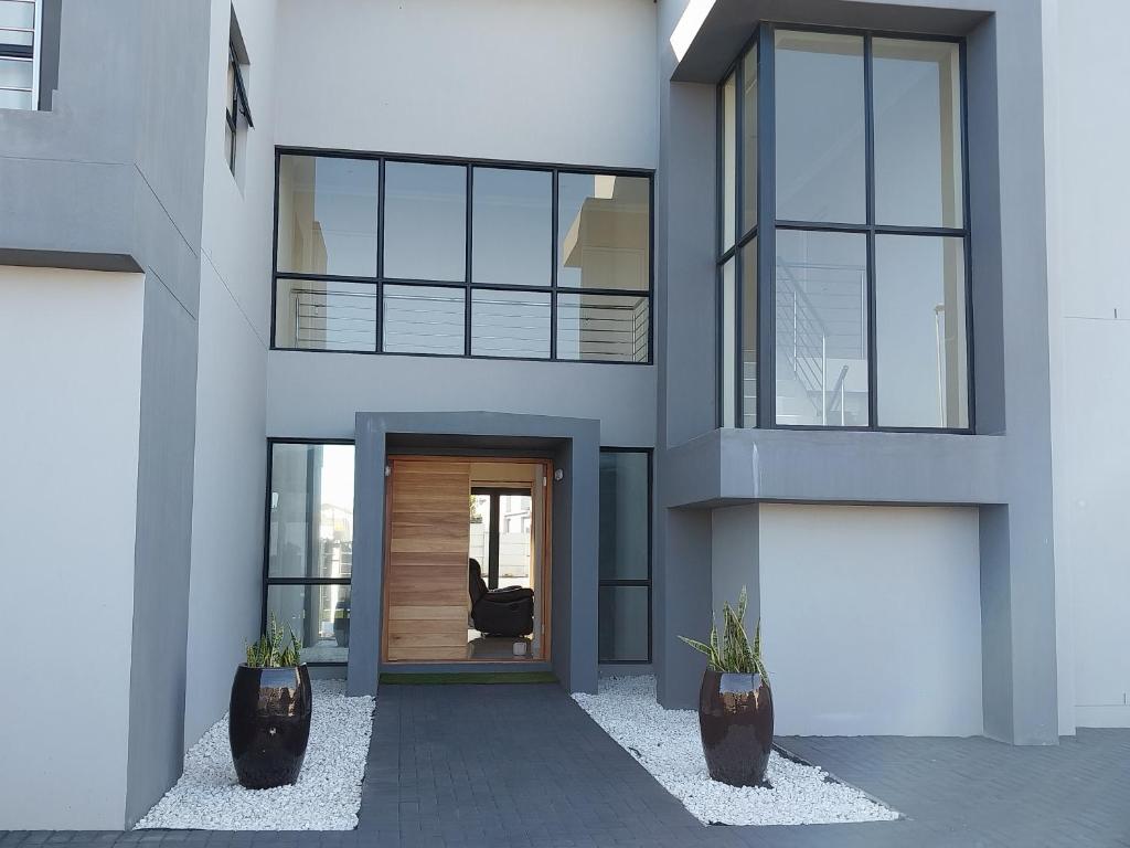 uma fachada de uma casa com uma porta e duas plantas em LND GUEST HOUSE em Bloubergstrand