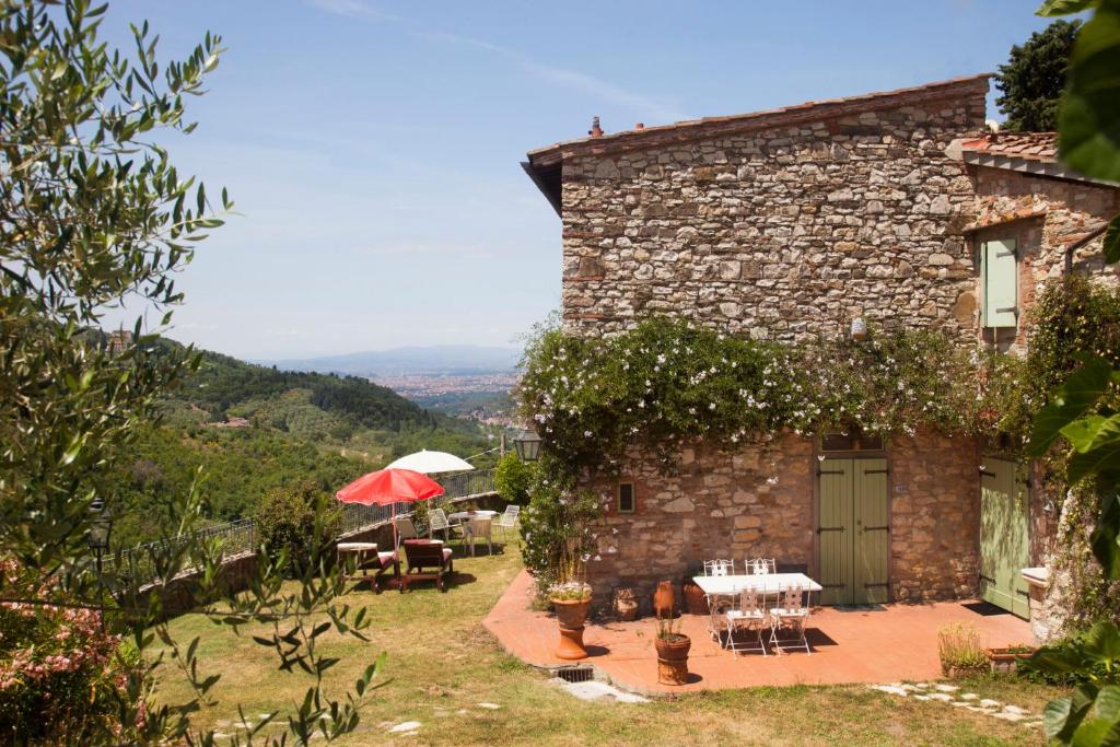 un edificio de piedra con mesas, sillas y sombrilla en Florence Villa Violetta, en Bagno a Ripoli