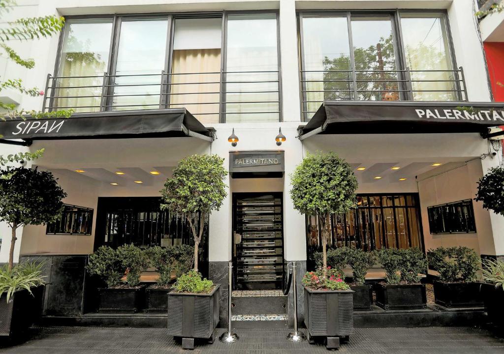 a building with two potted trees in front of it at Hotel Palermitano by DOT Boutique in Buenos Aires