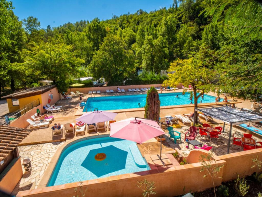 uma vista superior para uma piscina com cadeiras e guarda-sóis em Camping Hotel Les Rives du Loup em Tourrettes-sur-Loup