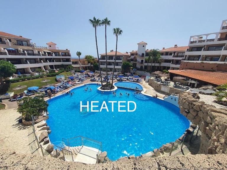 een verwarmd zwembad in een resort met een hotel bij Albatros Golf & Sea View in San Miguel de Abona