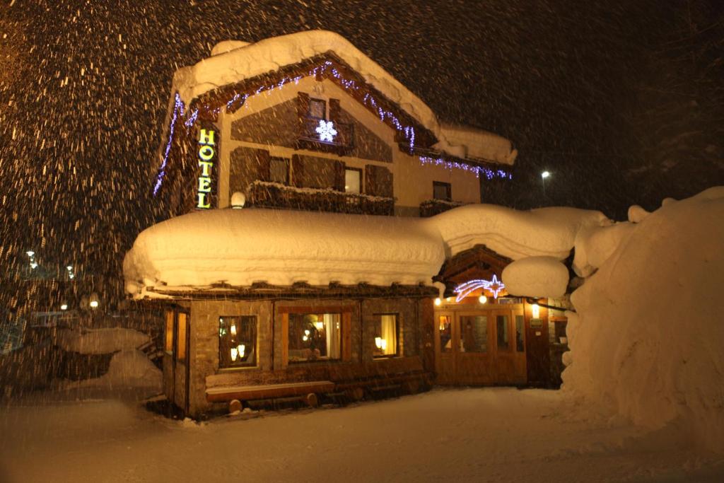 uma casa coberta de neve à noite em Hotel Stella Del Nord em Courmayeur