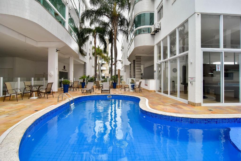 a large pool in a building with chairs and tables at 1 quadra da Praia em Canasvieiras, Piscina e Sala de Jogos P1881 in Florianópolis