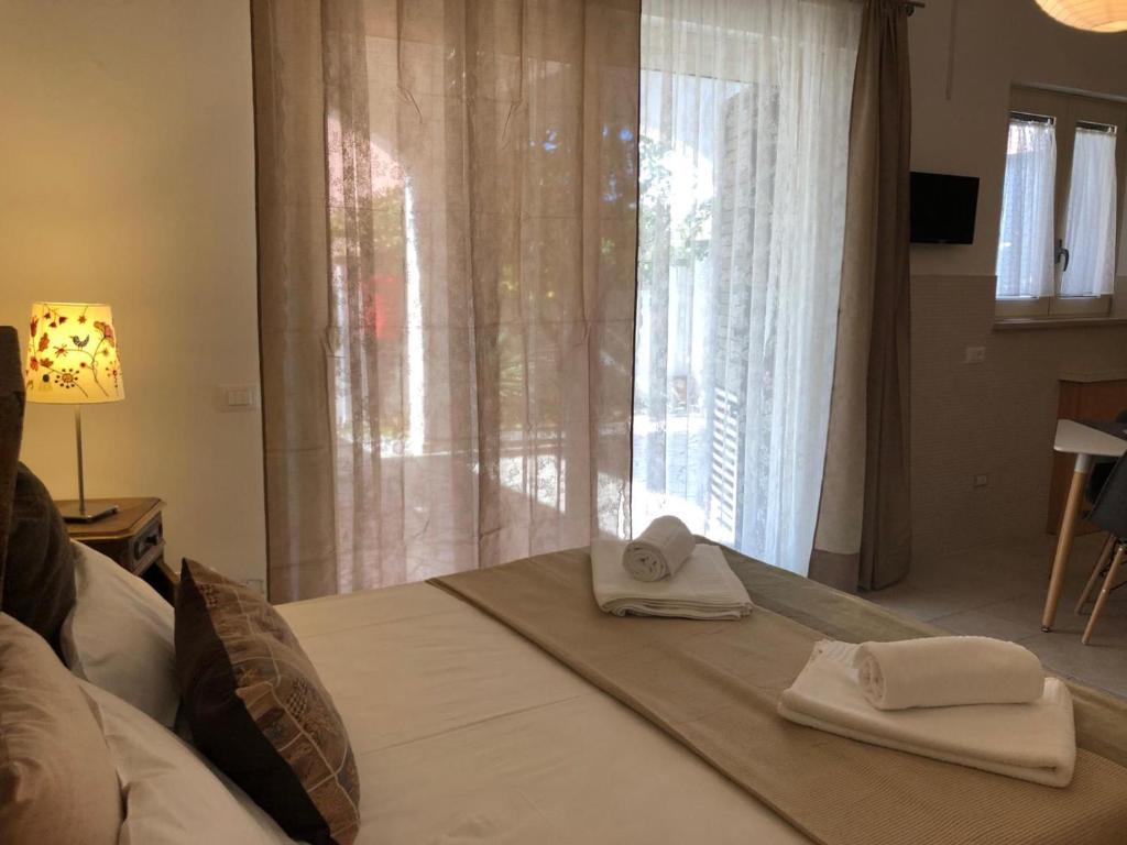 ein Bett mit Handtüchern und einem Fenster in der Unterkunft Odegos in Torre dell'Orso