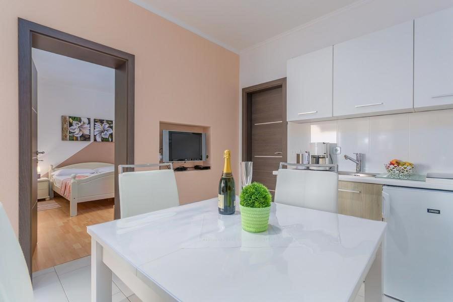 uma cozinha branca com uma garrafa de vinho no balcão em Apartment David em Novigrad Istria