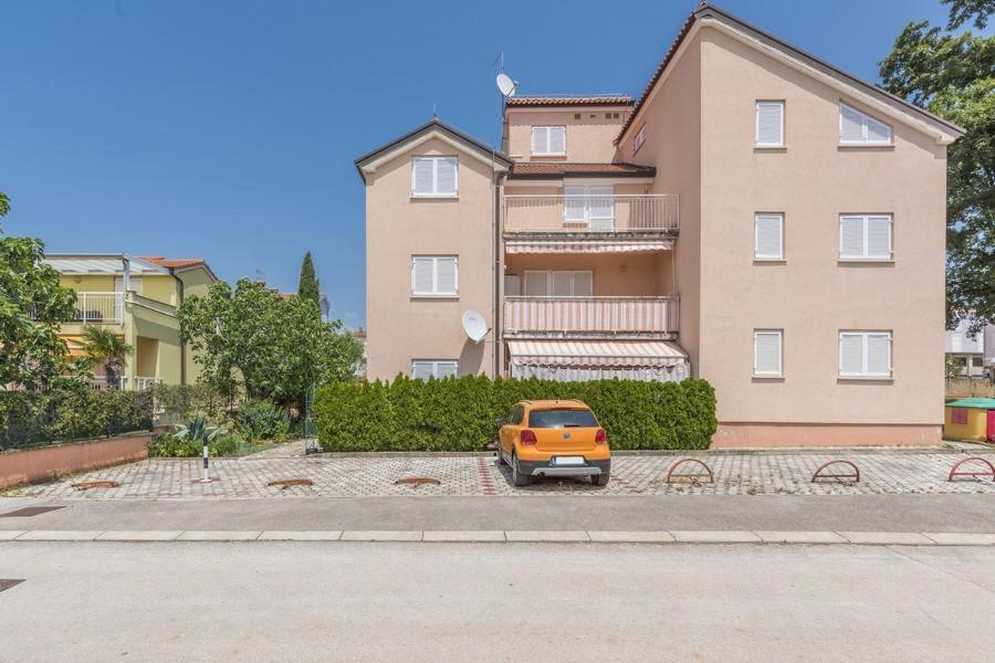 mały pomarańczowy samochód zaparkowany przed budynkiem w obiekcie Apartments Lovely Katarina w mieście Karigador