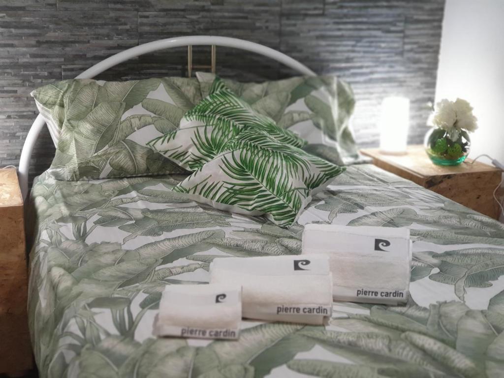 Cama con mantas y almohadas verdes y blancas en Casas de praia Sandra e Nelson, en Almada