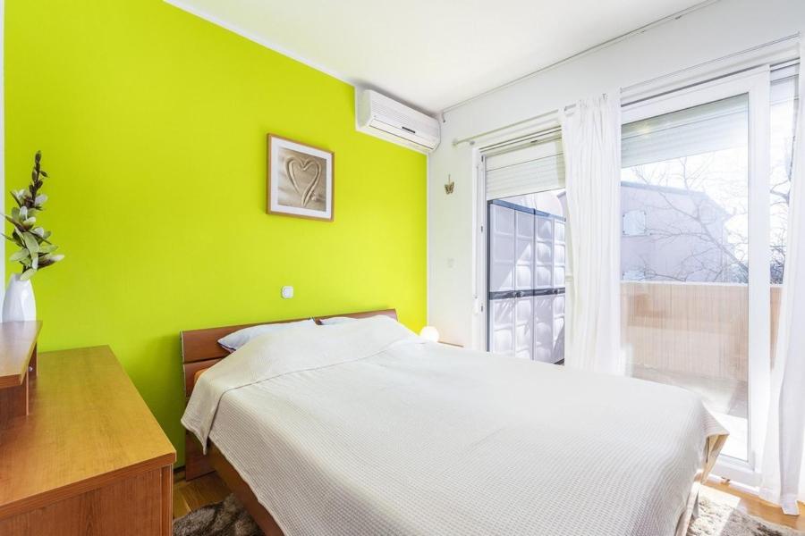 zieloną sypialnię z łóżkiem i oknem w obiekcie Apartment Carigo w mieście Karigador