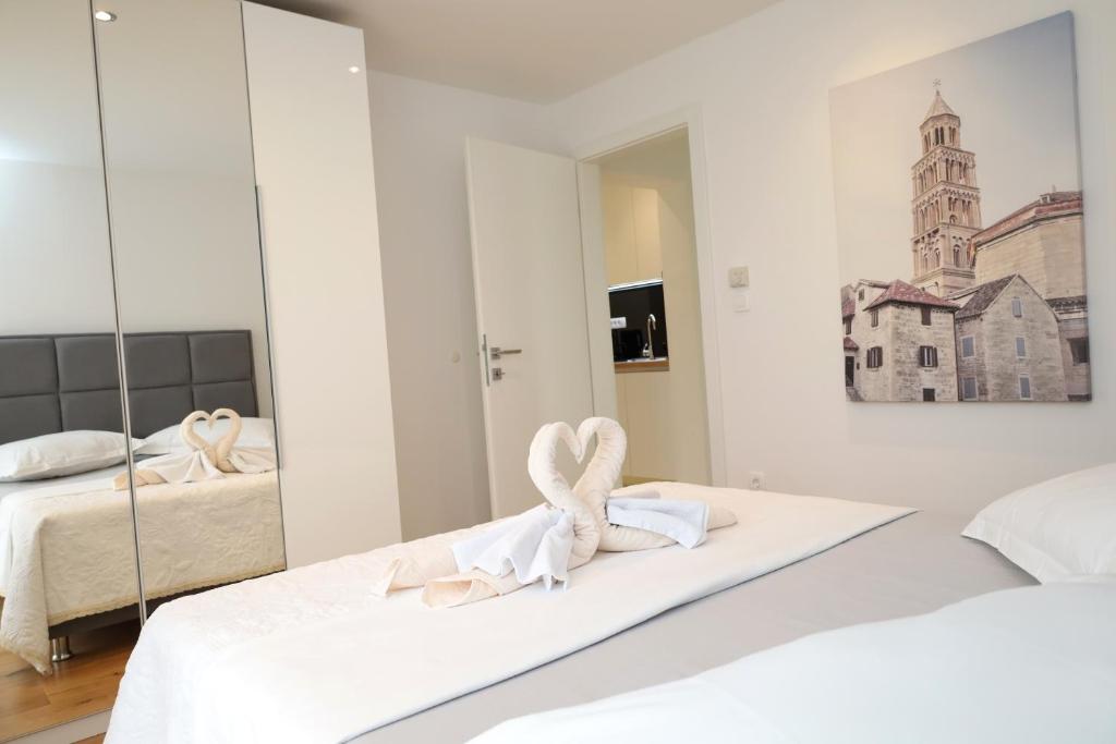 a white bedroom with two beds and a mirror at Dalmata D in Podstrana