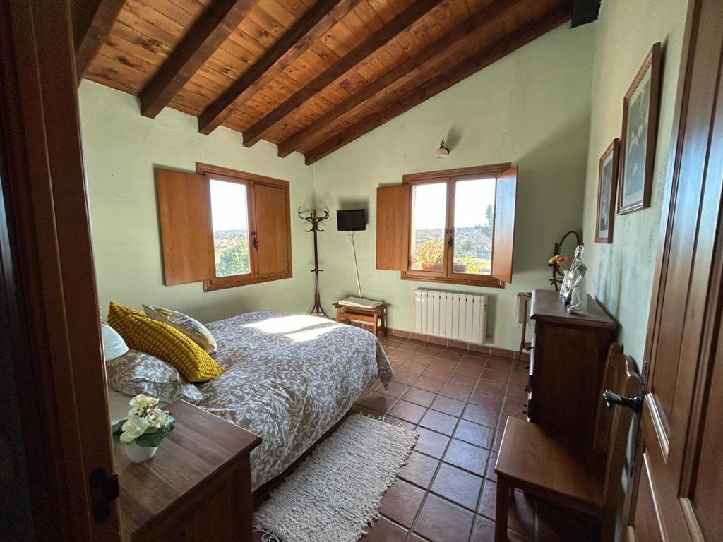 1 dormitorio con cama, mesa y ventanas en Casa Rural Roja, en Cebreros
