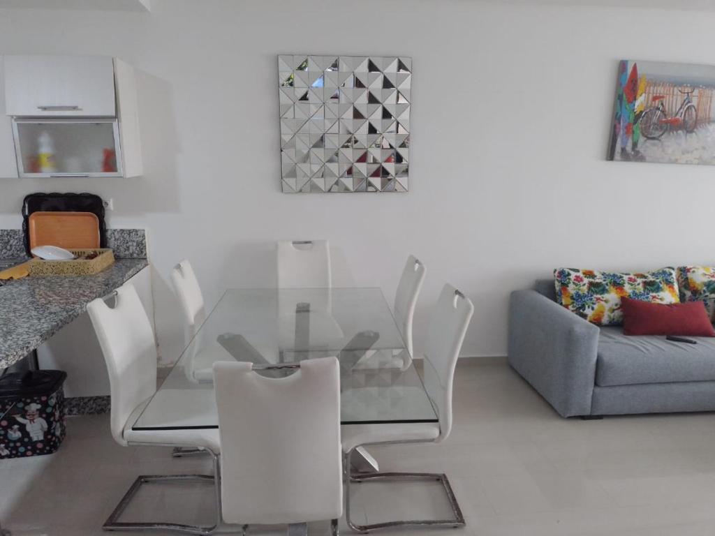 comedor con mesa de cristal y sillas blancas en Appartement ola blanca, en Sidi Rahal