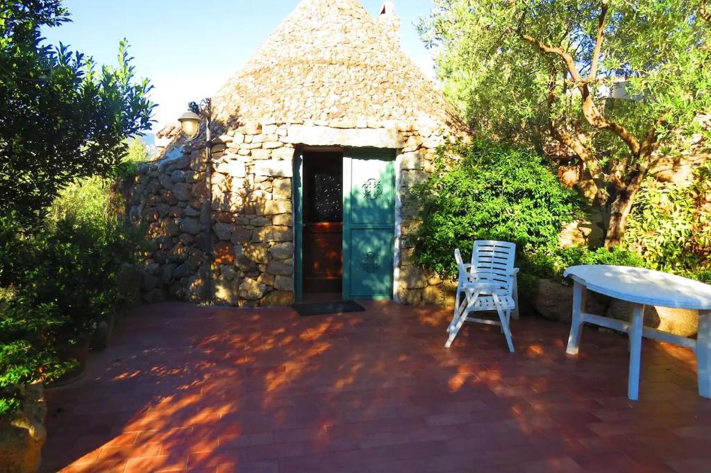 un piccolo edificio in pietra con un tavolo e sedie su un patio di Casa in campagna a Dorgali