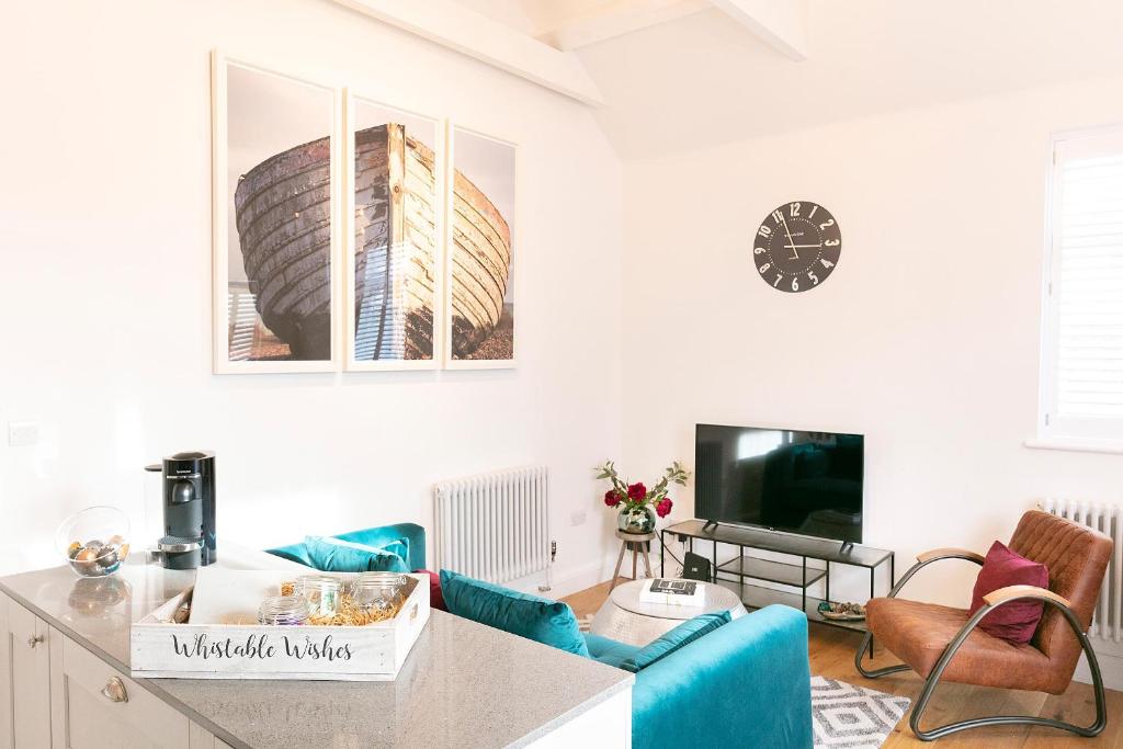 a living room with a blue couch and a tv at Whitstable Wishes, a Stylish Seaside Retreat, Whitstable with Parking Space in Whitstable