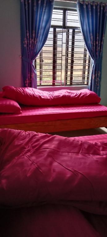 2 camas en una habitación con ventana y cortinas azules en Nhà Nghỉ Tấn Phúc en Thôn Phước Sơn