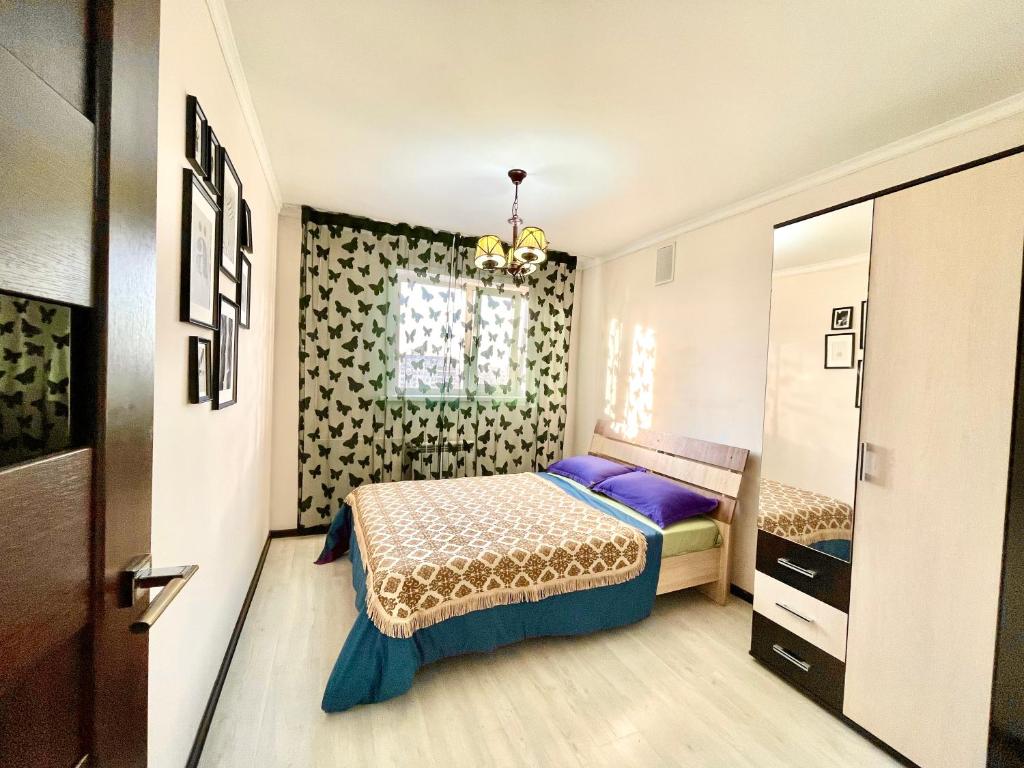 Schlafzimmer mit einem Bett und einem Fenster in der Unterkunft 2х комнатные апартаменты рядом с Центральной Мечетью in Pawlodar