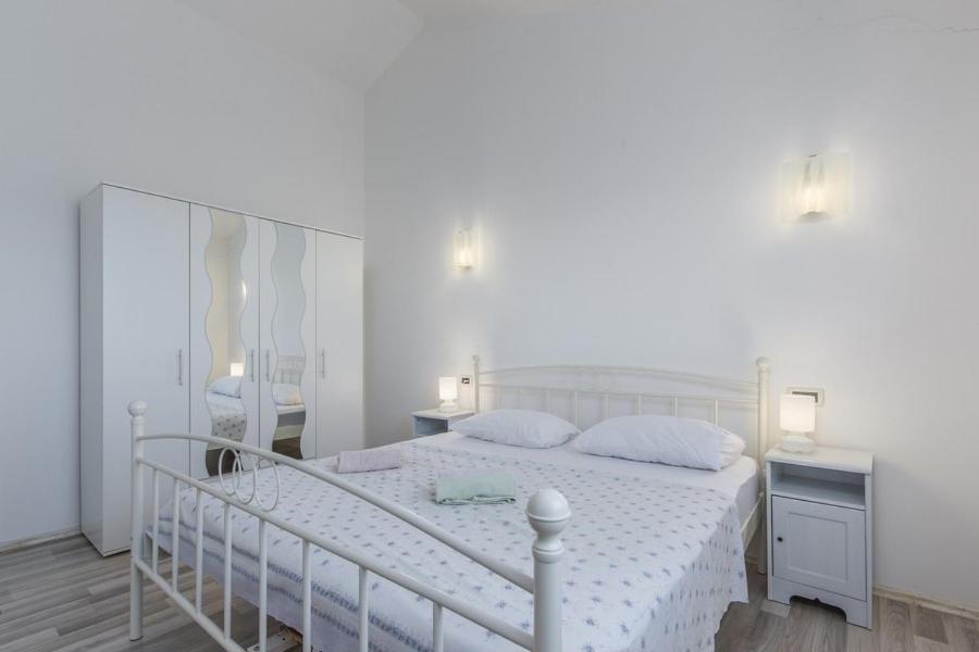 biała sypialnia z białym łóżkiem i lustrem w obiekcie Holiday Home Bianca w mieście Novigrad