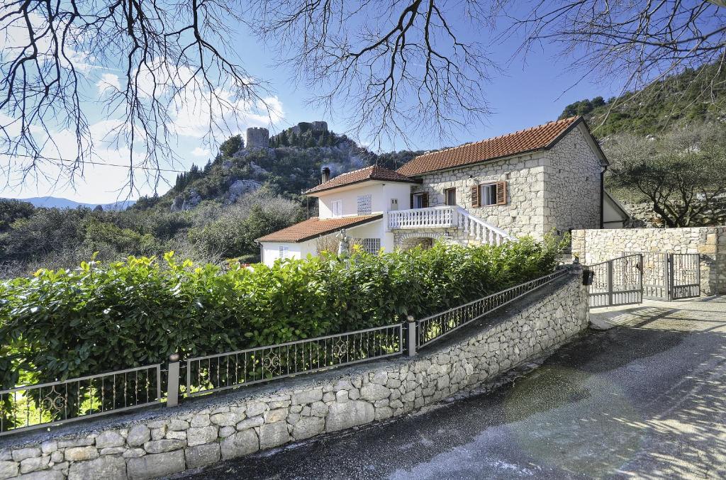 a house with a stone wall and a fence at Apartment Borovac in Vrgorac