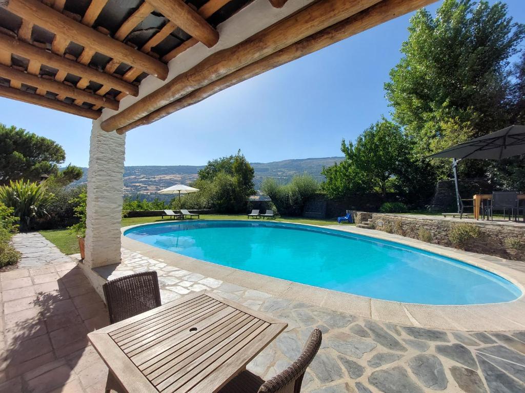 a swimming pool with a table and an umbrella at Casa de Alguaztar in Bubión