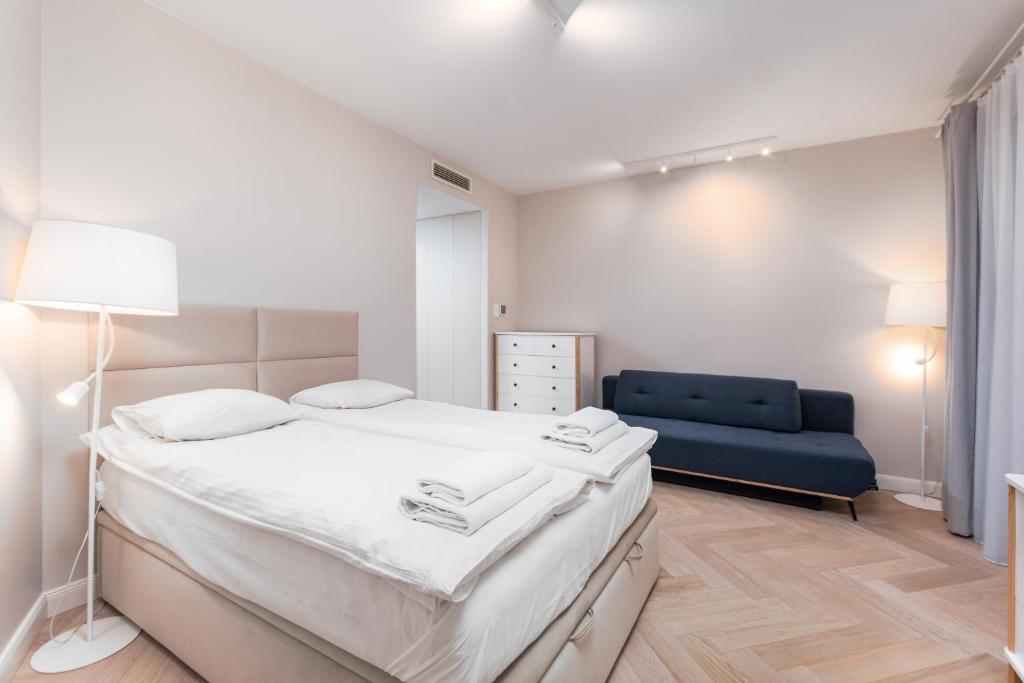 1 dormitorio con 1 cama y 1 sofá azul en Apartament Solidarności by Your Freedom, en Varsovia