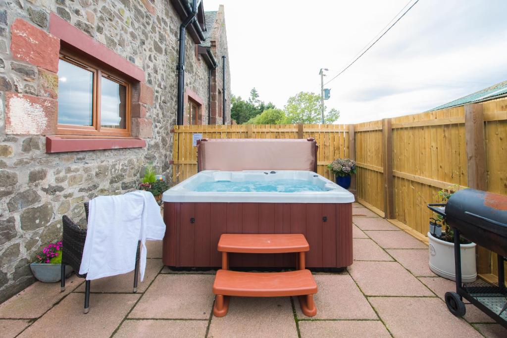 a hot tub on a patio with a stool at The Old Byre with Hot Tub in Forgandenny