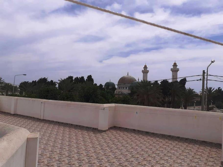 a white wall with a mosque in the background at Magnifique villa en Centre Ville in Monastir