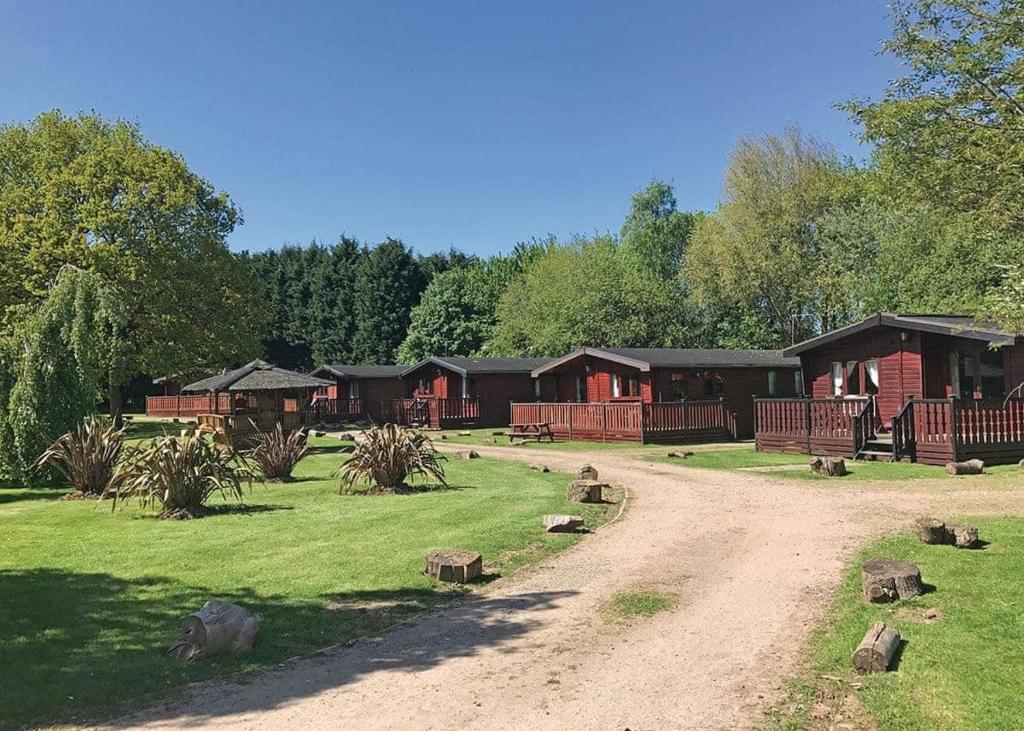 a group of cabins at a resort with a dirt road at Beechwood Park in Shardlow