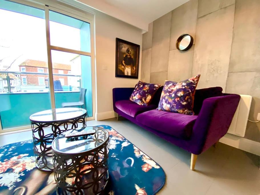 a living room with a purple couch and a table at Stunning Apartment - 1 Minute walk to Poole Quay - Great Location - Free Parking - Fast WiFi - Smart TV - Newly decorated - sleeps up to 2! Close to Poole & Bournemouth & Sandbanks in Poole