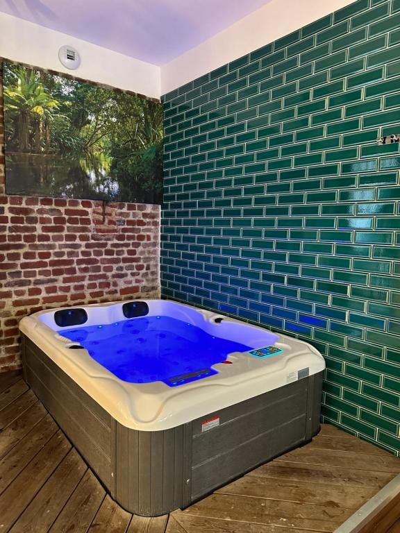 uma banheira de hidromassagem num quarto com uma parede de tijolos em La suite Brésilienne em Forges-les-Eaux