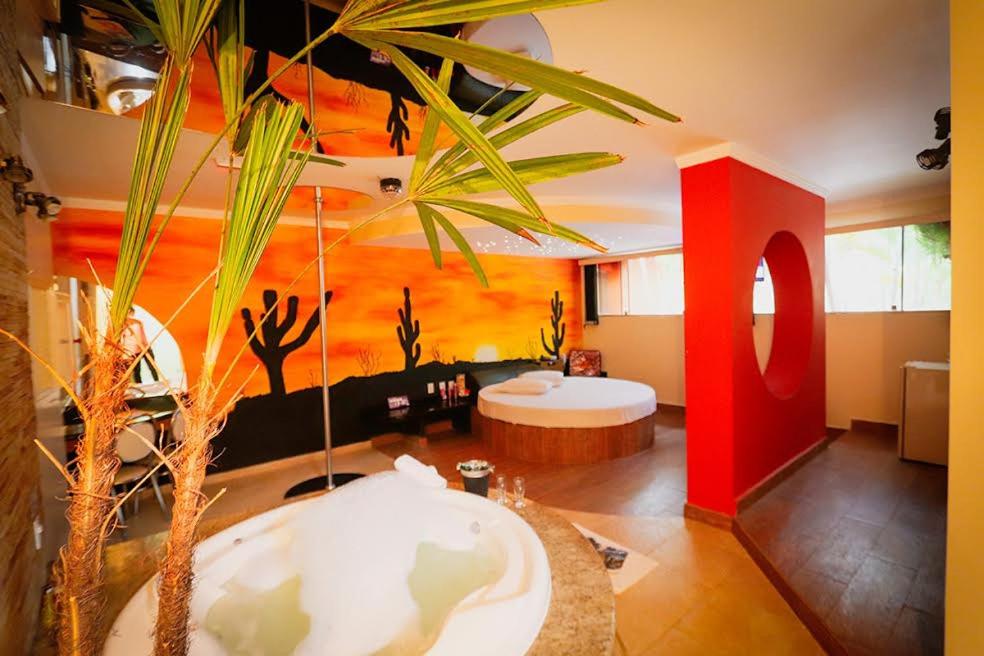 Motel Ipe في آراساريغواما: غرفة معيشة مع نخلة وحوض استحمام
