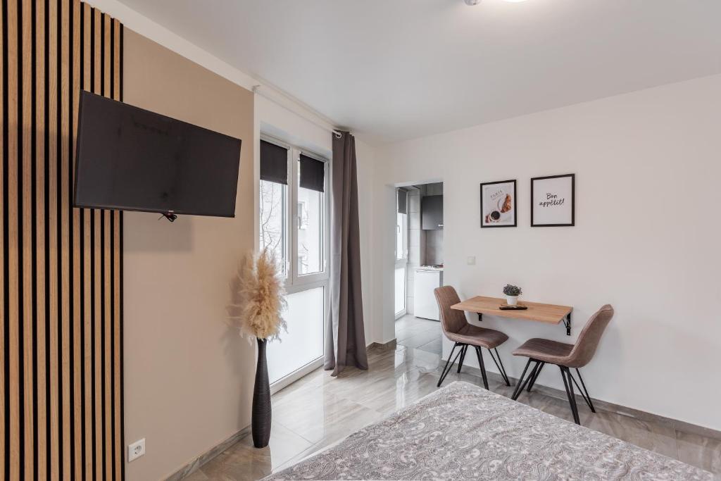 een woonkamer met een tv aan de muur en een tafel bij Apartments Cologne in Keulen