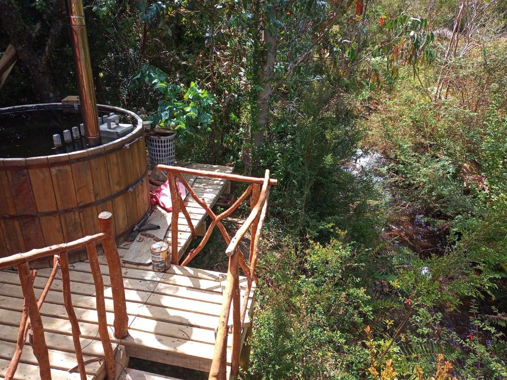 Refugio y Tinaja Curiñanco في فالديفيا: سطح خشبي مع كرسيين وحوض استحمام ساخن