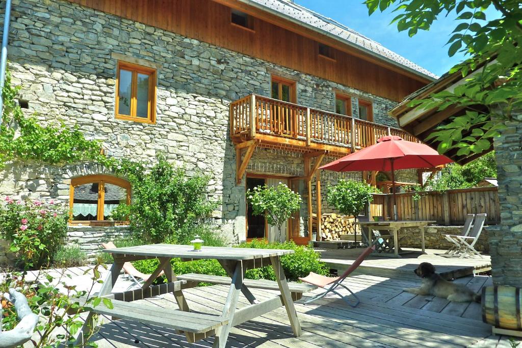 a stone house with a table and a patio at Le Moulin Ollivier in Saint-André-dʼEmbrun