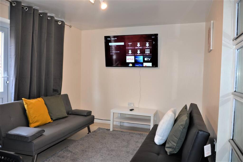 salon z kanapą i telewizorem na ścianie w obiekcie London 4 Bedroom House w Londynie