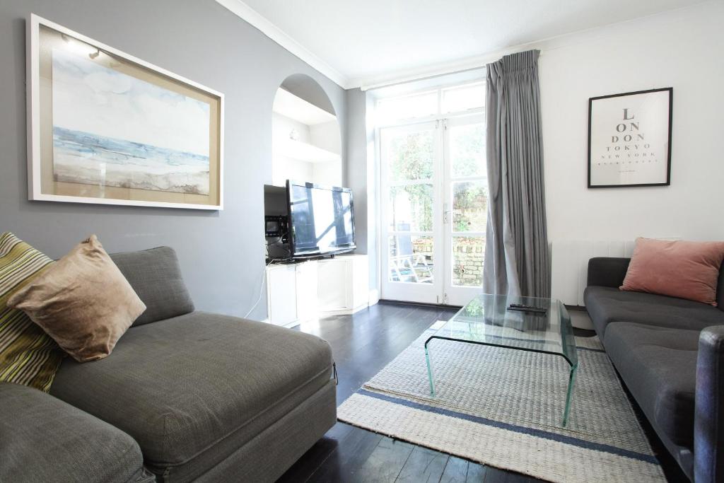 a living room with a couch and a glass table at Walk to Notting Hill /Paddington 1 B/R with patio in London