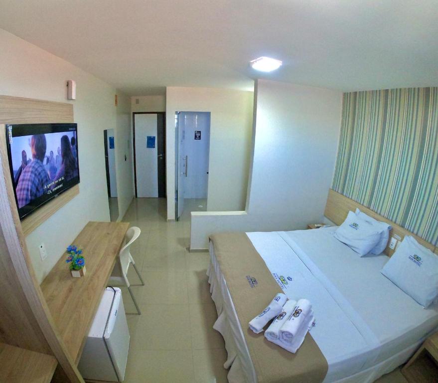 ein Hotelzimmer mit einem großen Bett und einem TV in der Unterkunft Max Hotel in Arcoverde